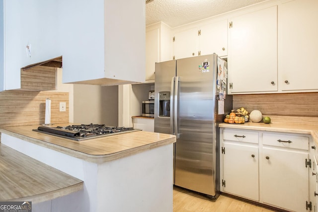 321 N Grove Blvd, Kingsland, GA 31548 - kitchen with stainless steel appliances, light countertops, white cabinetry, backsplash, and a textured ceiling