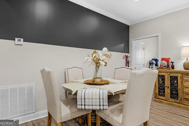 dining room featuring visible vents, wood finished floors, and ornamental molding