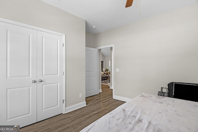 bedroom featuring baseboards, wood finished floors, ceiling fan, and a closet