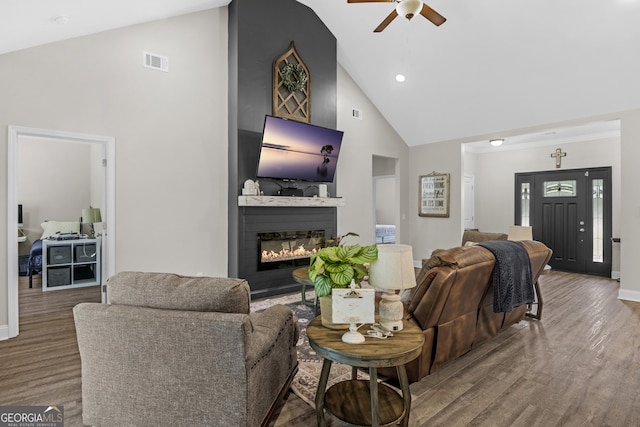 living room featuring wood finished floors, a large fireplace, ceiling fan, visible vents, and high vaulted ceiling