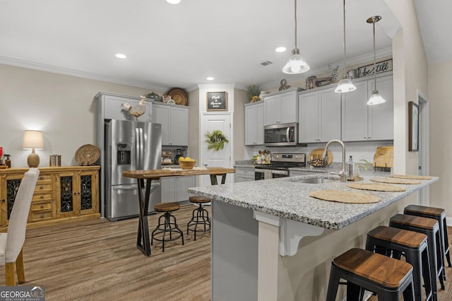 kitchen with a sink, stainless steel appliances, a kitchen breakfast bar, light stone counters, and a peninsula