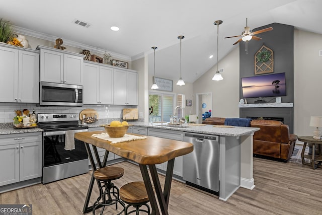 kitchen featuring light wood-style floors, appliances with stainless steel finishes, a sink, visible vents, and a peninsula