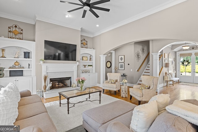 5841 Choctaw Ln, Braselton, GA 30517 - living room with a fireplace with raised hearth, crown molding, a ceiling fan, arched walkways, and wood finished floors