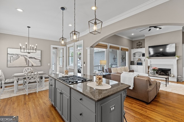 5841 Choctaw Ln, Braselton, GA 30517 - kitchen with light wood-style floors, stainless steel gas stovetop, a kitchen island, arched walkways, and gray cabinets