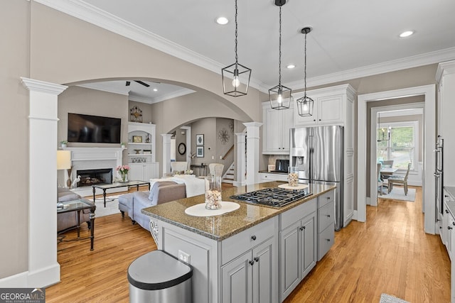 5841 Choctaw Ln, Braselton, GA 30517 - kitchen with arched walkways, light stone counters, appliances with stainless steel finishes, a kitchen island, and white cabinetry