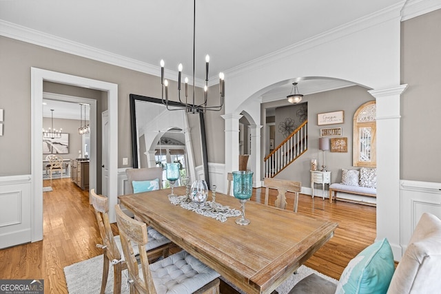 5841 Choctaw Ln, Braselton, GA 30517 - dining room featuring ornate columns, light wood-type flooring, ornamental molding, and arched walkways