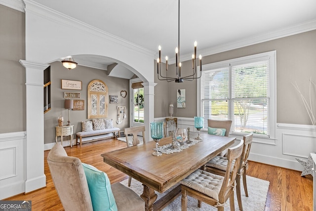 5841 Choctaw Ln, Braselton, GA 30517 - dining room featuring arched walkways, an inviting chandelier, light wood-style flooring, ornamental molding, and a wainscoted wall