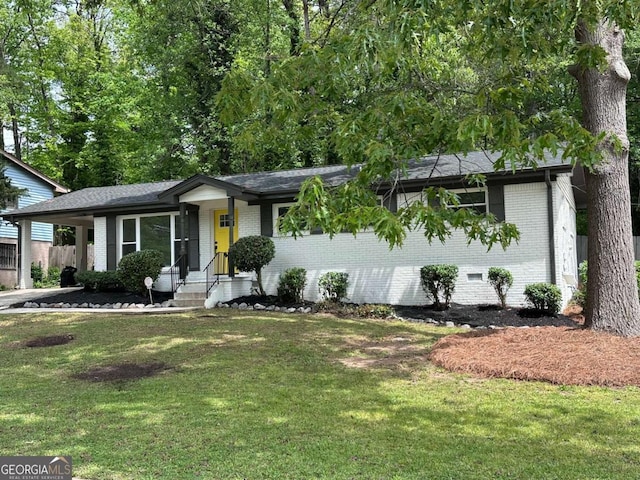 ranch-style home featuring fence, a shingled roof, a front yard, and brick siding