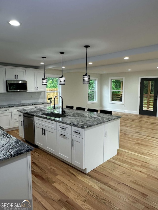 kitchen featuring white cabinets, a sink, light wood-style floors, stainless steel appliances, and recessed lighting