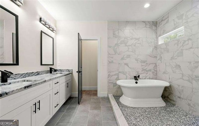 bathroom featuring double vanity, a soaking tub, recessed lighting, and a sink