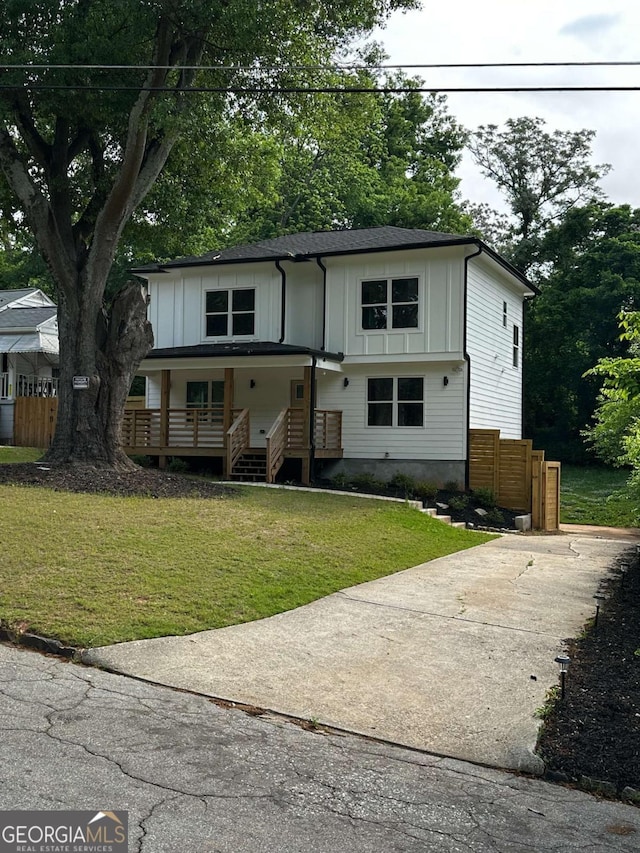 view of front of house with concrete driveway, board and batten siding, covered porch, fence, and a front lawn