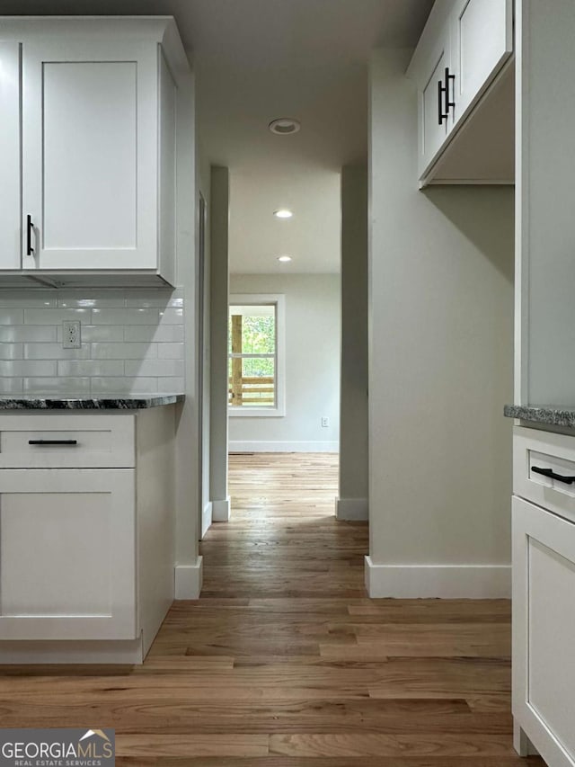 kitchen with recessed lighting, light wood-style floors, backsplash, baseboards, and white cabinets