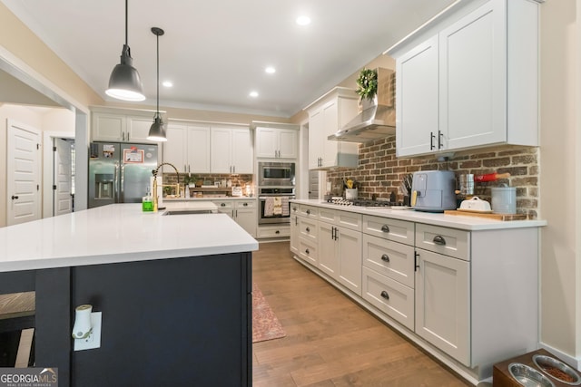 461 Preakness Way, Forsyth, GA 31029 - kitchen featuring wall chimney exhaust hood, appliances with stainless steel finishes, light countertops, hanging light fixtures, and backsplash