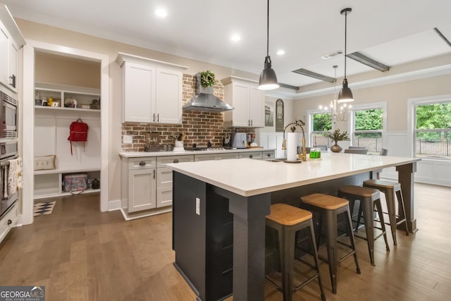 461 Preakness Way, Forsyth, GA 31029 - kitchen featuring wall chimney exhaust hood, appliances with stainless steel finishes, light countertops, an island with sink, and a kitchen bar