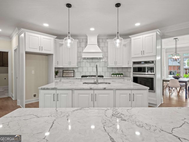 kitchen with decorative backsplash, custom exhaust hood, crown molding, and white cabinetry