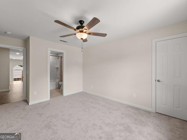 unfurnished bedroom featuring visible vents, baseboards, carpet, a ceiling fan, and ensuite bath