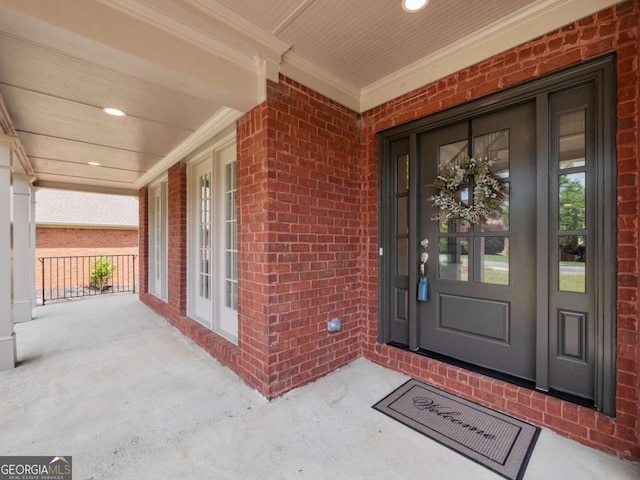 view of exterior entry with brick siding and a porch