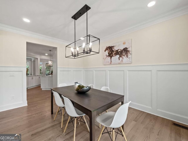 dining space featuring an inviting chandelier, crown molding, and a decorative wall