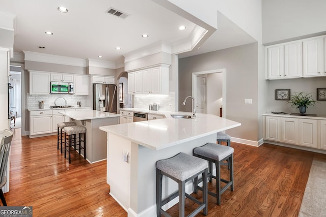 kitchen with a breakfast bar area, visible vents, crown molding, appliances with stainless steel finishes, and a sink