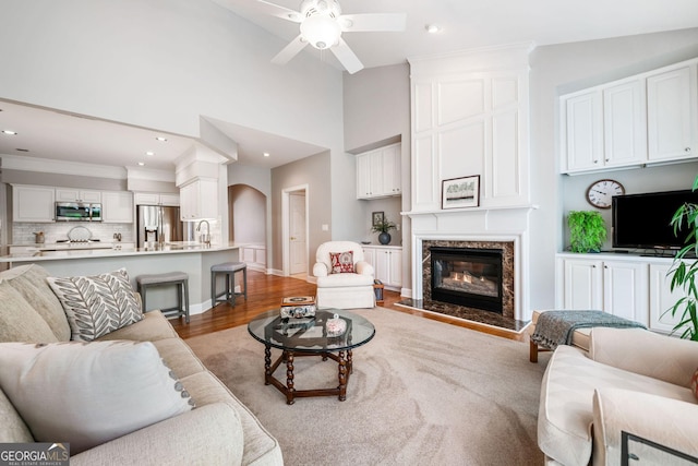 living room with a ceiling fan, vaulted ceiling, wood finished floors, recessed lighting, and a premium fireplace