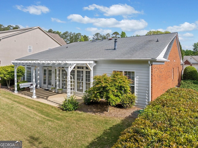 back of property with roof with shingles, a patio area, brick siding, a yard, and a pergola
