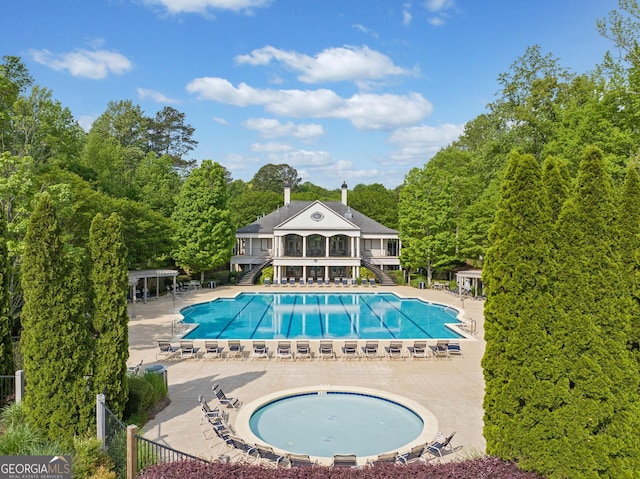 community pool featuring stairway, fence, and a patio area