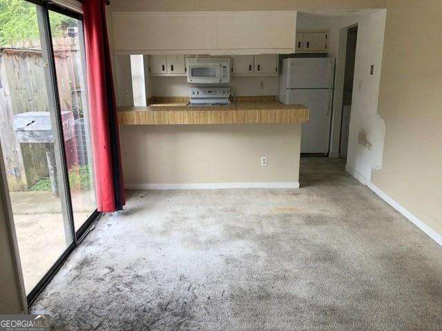2617 Terrace Pkwy, Morrow, GA 30260 - kitchen featuring white appliances, light colored carpet, white cabinets, baseboards, and a peninsula