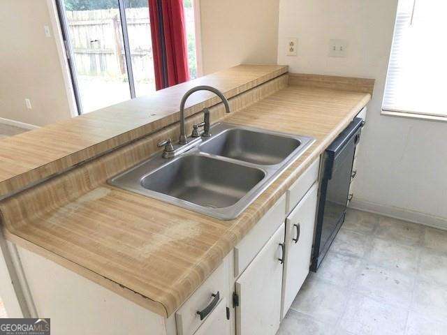 2617 Terrace Pkwy, Morrow, GA 30260 - kitchen featuring baseboards, light countertops, dishwasher, a sink, and white cabinetry
