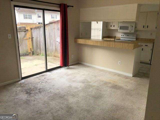 2617 Terrace Pkwy, Morrow, GA 30260 - kitchen with white microwave, light carpet, stove, and white cabinets