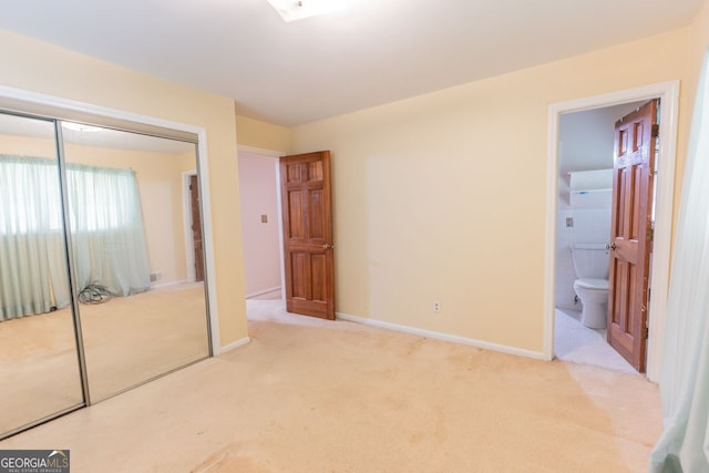 unfurnished bedroom featuring baseboards, ensuite bathroom, a closet, and carpet flooring