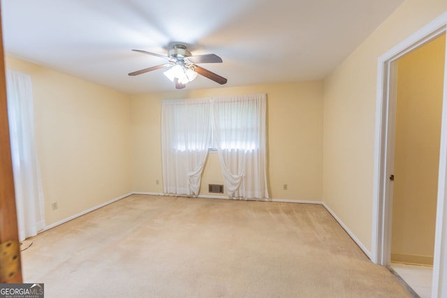 spare room with ceiling fan, baseboards, visible vents, and light carpet