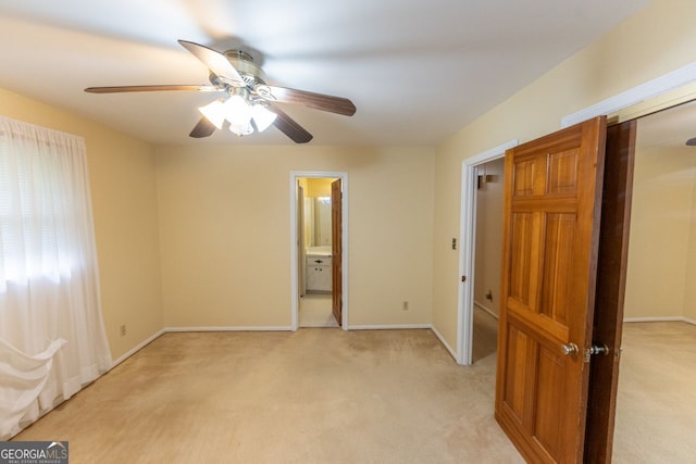 unfurnished bedroom with ceiling fan, ensuite bath, light colored carpet, and baseboards