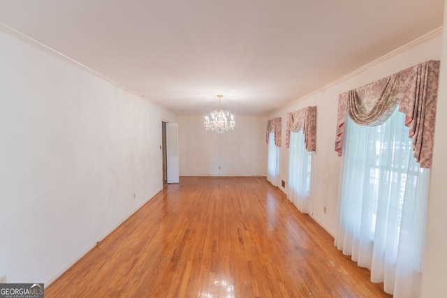unfurnished room with a chandelier, ornamental molding, and light wood finished floors