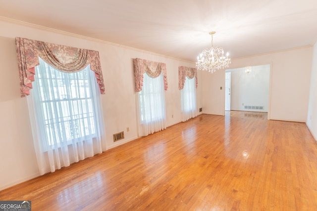 interior space featuring ornamental molding, light wood finished floors, visible vents, and a chandelier