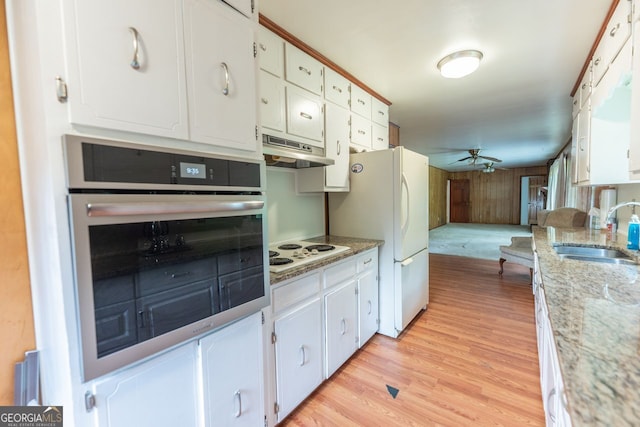 kitchen featuring white appliances, light wood-style floors, under cabinet range hood, a sink, and a ceiling fan
