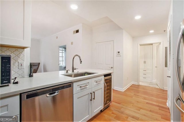 kitchen featuring visible vents, appliances with stainless steel finishes, a sink, white cabinets, and wine cooler