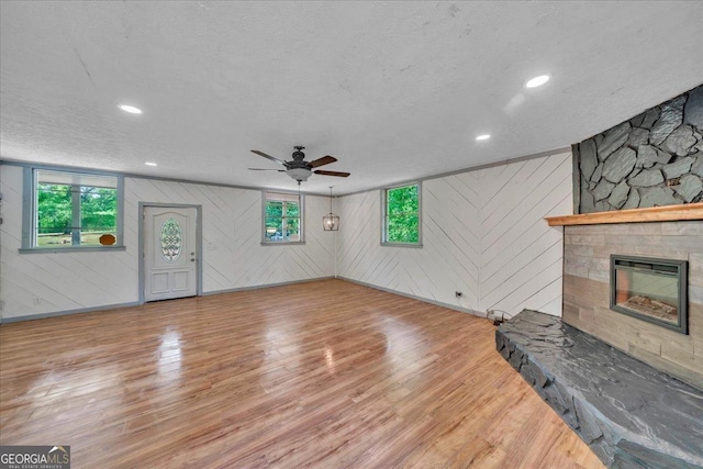 376 Mauldin Rd, Thomaston, GA 30286 - unfurnished living room with wood walls, wood finished floors, ceiling fan, and a stone fireplace