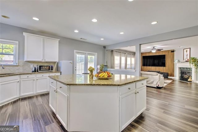 5845 Princeton Run Trl, Tucker, GA 30084 - kitchen with stainless steel microwave, a center island, light stone counters, a premium fireplace, and wood finished floors