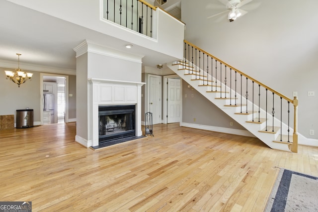 15635 US Highway 27 N, Hamilton, GA 31811 - unfurnished living room featuring wood-type flooring, a fireplace, baseboards, stairway, and ceiling fan with notable chandelier