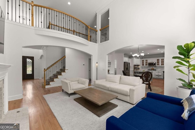 living room with an inviting chandelier, arched walkways, stairs, and a high ceiling