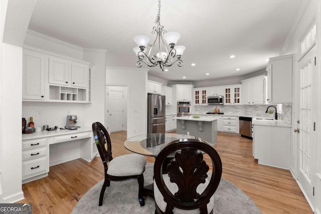 dining space featuring crown molding, built in study area, a chandelier, light wood-style floors, and recessed lighting