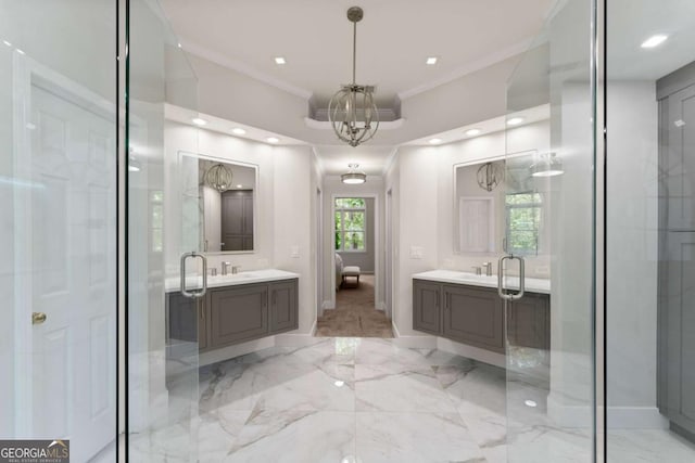 bathroom with crown molding, a chandelier, marble finish floor, baseboards, and two vanities
