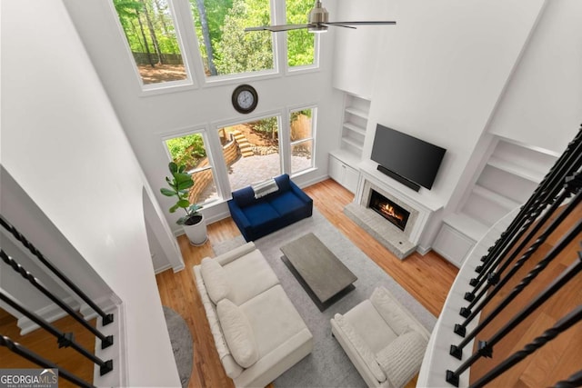 1900 Chattahoochee Run Dr, Suwanee, GA 30024 - living area featuring healthy amount of natural light, a brick fireplace, wood finished floors, a high ceiling, and a ceiling fan