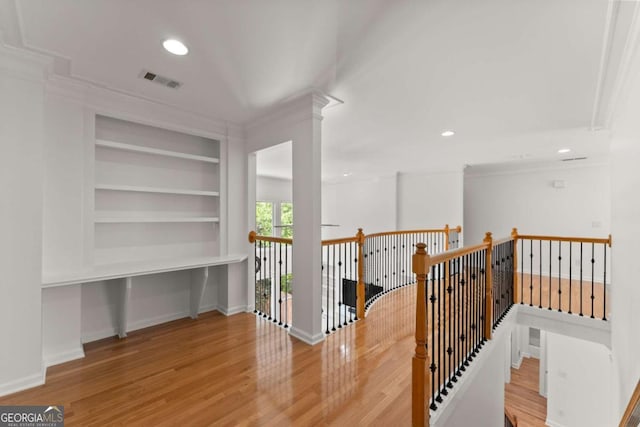 hallway with baseboards, visible vents, built in features, and wood finished floors