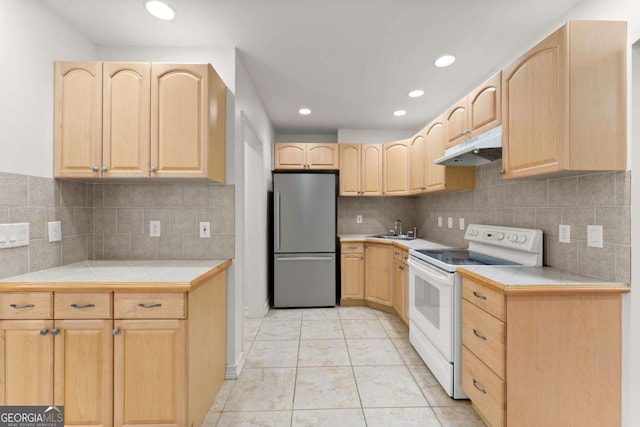 kitchen featuring freestanding refrigerator, light brown cabinetry, under cabinet range hood, and white electric range