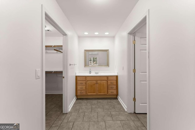 bathroom featuring baseboards, tile patterned floors, a walk in closet, and vanity