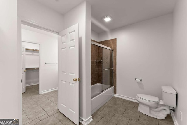bathroom featuring bath / shower combo with glass door, tile patterned flooring, baseboards, and toilet