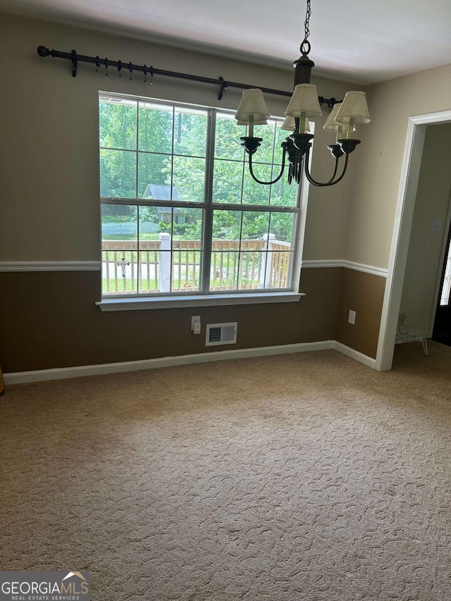 unfurnished dining area featuring baseboards, visible vents, an inviting chandelier, and carpet