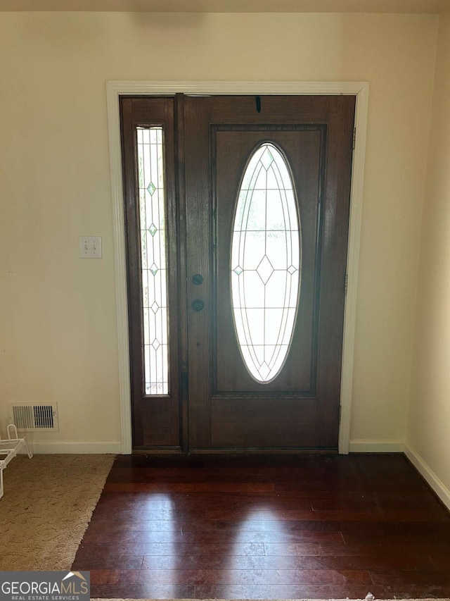 foyer featuring visible vents, baseboards, a healthy amount of sunlight, and dark wood-type flooring