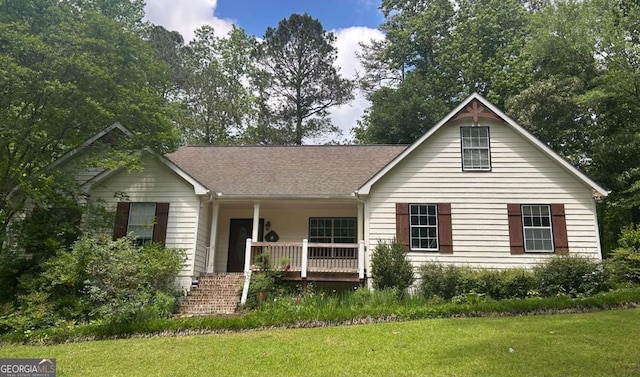 view of front of house with a porch, a front lawn, and roof with shingles